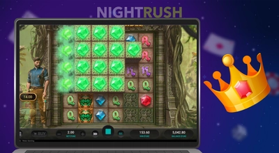Laptop showing Ancient Tumble slot with green gem symbols next to a gold crown icon.