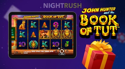 Tablet displaying the John Hunter and the Book of Tut slot game next to a red gift box.
