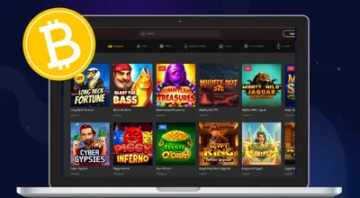 Laptop displaying a crypto casino with various slot game titles and a Bitcoin symbol.